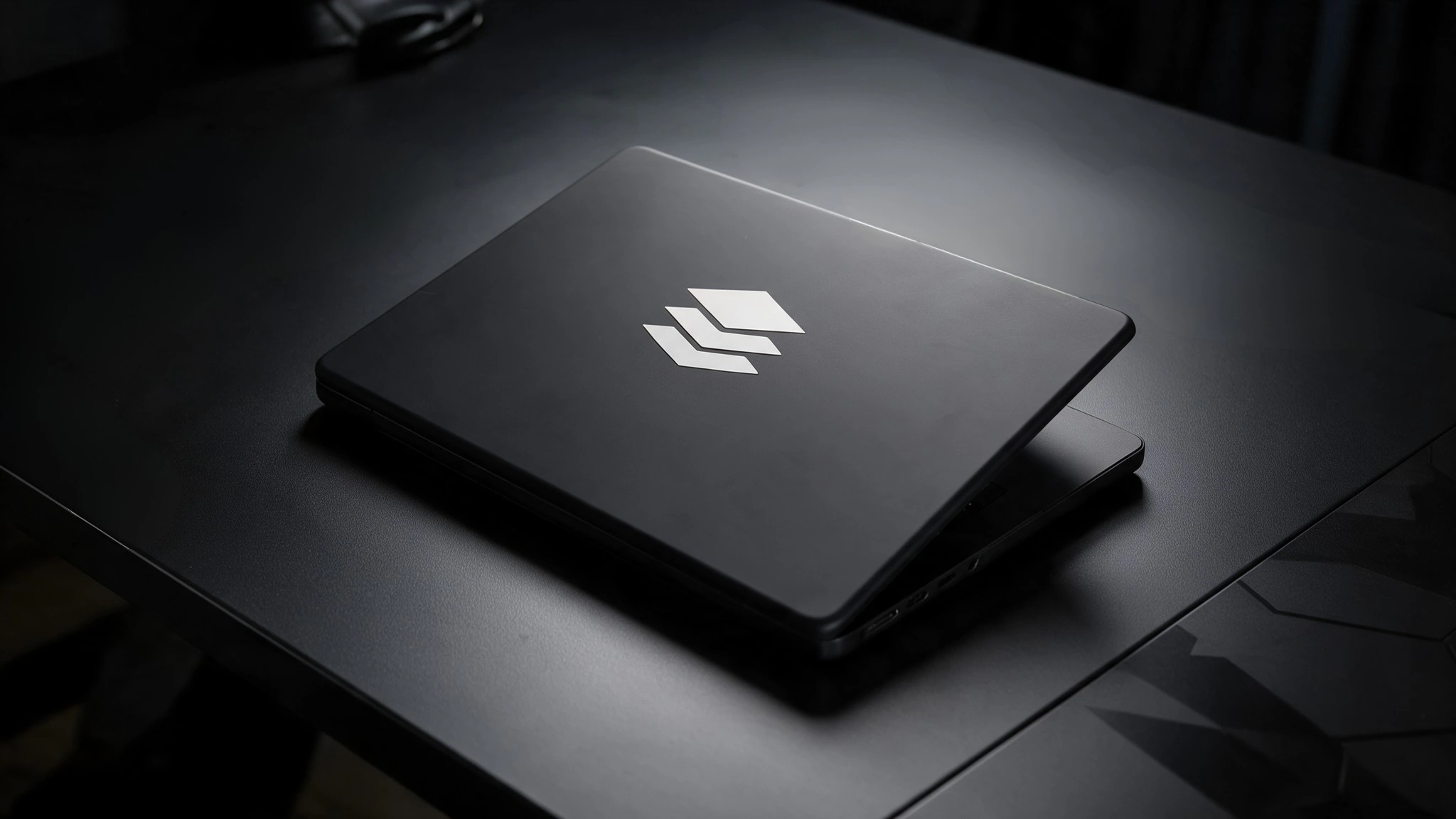 Closed laptop with the Veronix mark on a dark desk
